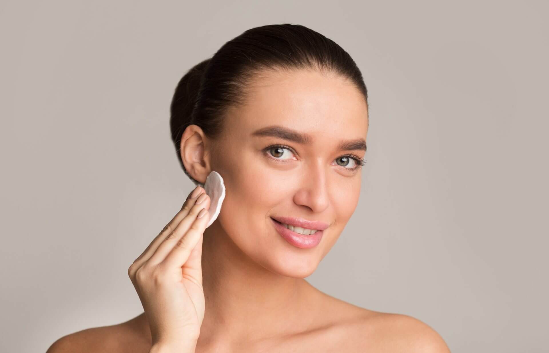 Millennial girl with perfect skin removing make up with cotton pad